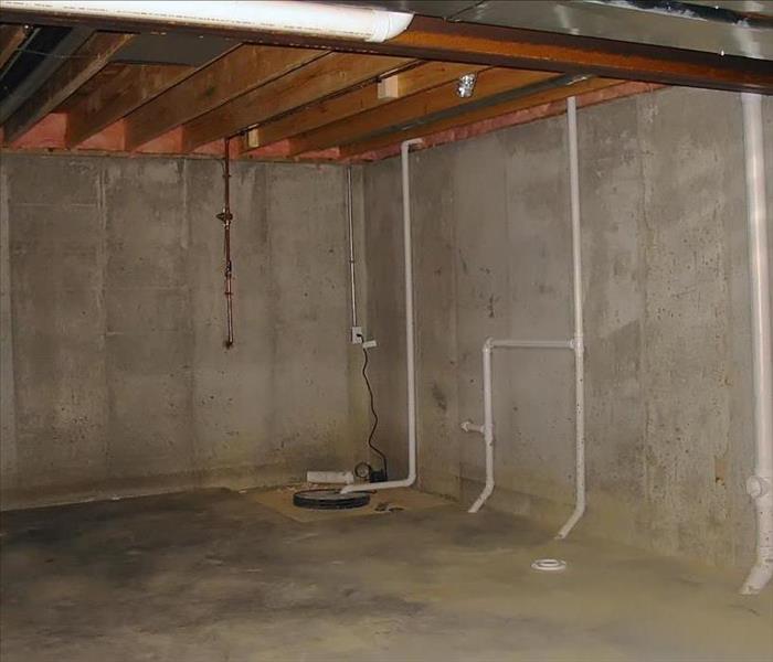 concrete pad in basement, plumbing lines on concrete walls, ceiling joists.